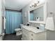 Modern bathroom with a marble-top vanity, stylish mirror, and a shower with blue curtain at 4851 Ne 7Th St, Ocala, FL 34470