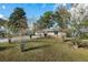 Spacious front yard with mature trees surrounding a cozy, one-story home, creating a peaceful setting at 4851 Ne 7Th St, Ocala, FL 34470