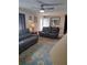 Bright living room featuring two gray reclining sofas, a ceiling fan, and a floral area rug at 11301 Huggins St, Leesburg, FL 34788