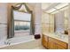 Relaxing bathroom with a garden tub, draped window, and vanity with double sinks at 8929 Sw 196Th Ct, Dunnellon, FL 34432