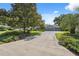 Beautiful front exterior showcasing a manicured lawn, mature trees, and a long driveway leading to a three-car garage at 8929 Sw 196Th Ct, Dunnellon, FL 34432