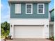 A two-story home showcasing a white garage door, white trim, teal siding, and large windows at 1125 Red Buckeye Ct, Deland, FL 32720