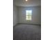 Bright bedroom with neutral carpet, paint, and a window providing outdoor views at 1133 Red Buckeye Ct, Deland, FL 32720