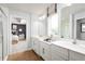 Well-lit bathroom featuring double sinks, white cabinets, wood flooring, and shower at 6408 Domizio Dr, Winter Haven, FL 33884