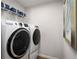 Modern laundry room with front load washer and dryer, wire rack shelving, and light-colored walls at 6408 Domizio Dr, Winter Haven, FL 33884
