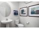 Elegant powder room features a pedestal sink, round mirror, and decorative artwork at 6408 Domizio Dr, Winter Haven, FL 33884