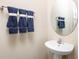 Chic powder room with pedestal sink, oval mirror, and decorative blue towels at 6505 Domizio Dr, Winter Haven, FL 33884