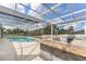 Outdoor kitchen with stone accents near sparkling pool within screened enclosure at 1148 Rosetta Dr, Deltona, FL 32725