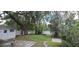 Backyard featuring a large tree, lush greenery, a white fence, and a small patio area at 423 E Kaley St, Orlando, FL 32806