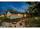 The backyard features a screen porch with lights shining from the home's windows at twilight at 7289 Lake Floy Cir, Orlando, FL 32819