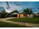 Home exterior at twilight showcasing a two car garage and green lawn at 7289 Lake Floy Cir, Orlando, FL 32819