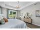 Bright main bedroom featuring a large window with a view, tray ceiling with modern chandelier, and a stylish console table at 855 Emerald Grove Dr, Apopka, FL 32703