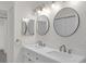 Bright bathroom featuring a double vanity with round mirrors and modern fixtures at 3207 Cr 419, Lake Panasoffkee, FL 33538