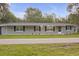 Charming home with a gray facade, black shutters, manicured lawn, and inviting curb appeal at 3207 Cr 419, Lake Panasoffkee, FL 33538