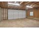 Spacious garage with white door, concrete floor, wooden framing, and overhead lighting offers ample room for vehicles and storage at 3207 Cr 419, Lake Panasoffkee, FL 33538