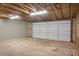 Spacious garage with gray door, concrete floor, gray walls, and overhead lighting offers ample room for vehicles and storage at 3207 Cr 419, Lake Panasoffkee, FL 33538