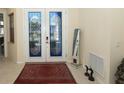Elegant foyer featuring decorative glass double doors, tile flooring, and ample natural light at 255 Royal Palm Dr, Davenport, FL 33837