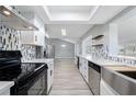 Modern kitchen with stainless steel appliances, white cabinetry, and gray backsplash at 3240 Flamingo Ln, Mulberry, FL 33860
