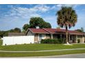 Tan house with red roof, white fence, and palm tree at 11432 Cardiff Dr, Orlando, FL 32837