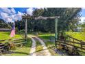 Charming ranch entrance with a wooden 'Welcome to the Ranch' sign, flanked by an American flag and gated fence at 4292 Sw 73Rd Trl, Bushnell, FL 33513