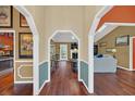 Hallway with hardwood floors, arched doorways, and view of the living room and kitchen at 8847 Rose Hill Dr, Orlando, FL 32818