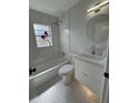 Bright bathroom with tiled shower over tub, modern vanity, and unique hexagonal floor tiles at 766 Bates Sw Ave, Winter Haven, FL 33880