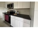 Stylish kitchen with stainless steel oven and microwave, complimented by white cabinets and dark countertop at 766 Bates Sw Ave, Winter Haven, FL 33880