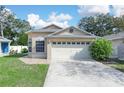 Tan one-story house with a white garage door and landscaped lawn at 2907 Willow Oak Ct, Kissimmee, FL 34744