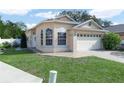 Tan one story house with a white garage door and landscaped lawn at 2907 Willow Oak Ct, Kissimmee, FL 34744