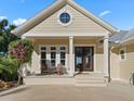 House exterior featuring a covered porch, tan siding, and landscaping at 12943 Se Sunset Harbor Rd, Weirsdale, FL 32195