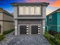 Contemporary home with gray stone exterior and a two-car garage at 1544 Corolla Ct, Reunion, FL 34747