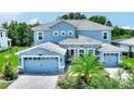 Beautiful two-story house with light blue exterior, stone accents, and a three-car garage at 1457 Olympic Club Blvd, Champions Gate, FL 33896