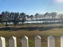 View of lake from backyard with white picket fence at 124 Dakota Ave, Groveland, FL 34736