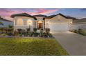 One-story house exterior at dusk, featuring a two-car garage and landscaping at 11276 Se 170Th Pl, Summerfield, FL 34491
