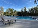 Community pool with lounge chairs and surrounding trees at 5124 Conroy Rd # 27, Orlando, FL 32811