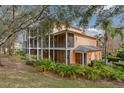 Exterior view of a home with multiple screened balconies surrounded by lush greenery and mature trees at 301 New Providence Promenade, Davenport, FL 33897