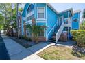 Charming blue condo featuring multiple windows, a small palm tree, and convenient stairwell access to the entrance at 2735 N Poinciana Blvd # 103, Kissimmee, FL 34746