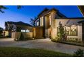 Modern two-story home featuring manicured landscaping and an inviting paved driveway and walkway, lit for evening at 1691 Chestnut Ave, Winter Park, FL 32789
