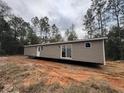 A modern home with taupe siding is being installed on a lot with red dirt and tall pine trees at 10129 Sw 157Th Ln, Dunnellon, FL 34432