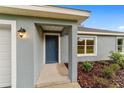 Close-up of the home's entry featuring a stylish blue door, modern lighting, and attractive landscaping at 15673 Sw 37 Cir, Ocala, FL 34482