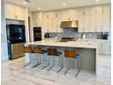 Modern kitchen with stainless steel appliances, large center island with seating, and tile backsplash at 16832 Bolsena Dr, Bella Collina, FL 34756