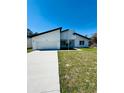 Contemporary home with white exterior, a two-car garage, and a smooth concrete driveway on a sunny day at 1314 Congo Ct, Poinciana, FL 34759