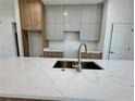 Modern kitchen island with marble countertop, stainless steel sink and faucet, and wood paneled cabinets at 1314 Congo Ct, Poinciana, FL 34759