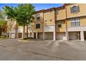 View of the townhome exteriors with stucco facade, garages, and well-maintained landscaping at 6121 Metrowest Blvd # 103, Orlando, FL 32835