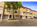 View of the townhome exteriors with stucco facade, garages, and well-maintained landscaping at 6121 Metrowest Blvd # 103, Orlando, FL 32835