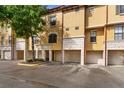 View of the townhome exteriors with stucco facade, garages, and well-maintained landscaping at 6121 Metrowest Blvd # 103, Orlando, FL 32835