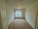 This carpeted bedroom features a ceiling fan and a large window offering natural light at 1678 Swallowtail Ln, Sanford, FL 32771