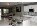 Modern kitchen featuring white cabinets, granite countertops, stainless steel appliances, and an island with seating at 1991 Sanderlin Point Loop, Apopka, FL 32703