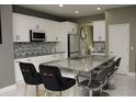 Modern kitchen with white cabinetry, stainless steel appliances, and a large island with granite countertop and seating at 1991 Sanderlin Point Loop, Apopka, FL 32703