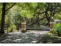 A wrought iron gate between two stone pillars marks the entrance to the estate at 445 Se 98Th Ave, Webster, FL 33597